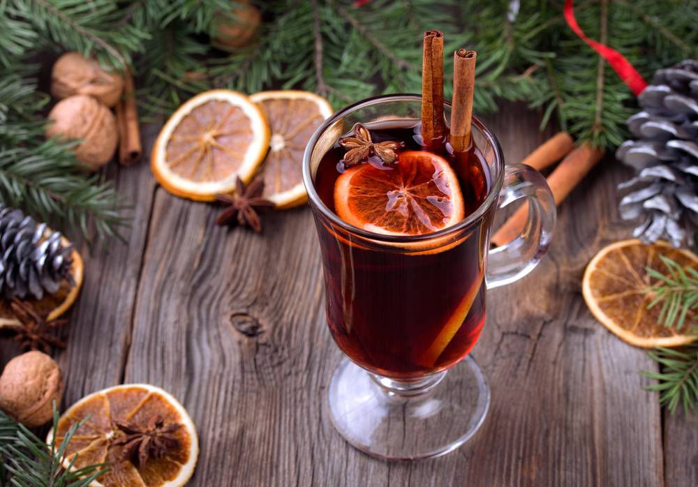 Mulled wine and spices. Sliced dried orange, cinnamon sticks and anise stars with pine brunch and candle. Christmas decoration over wooden background. .